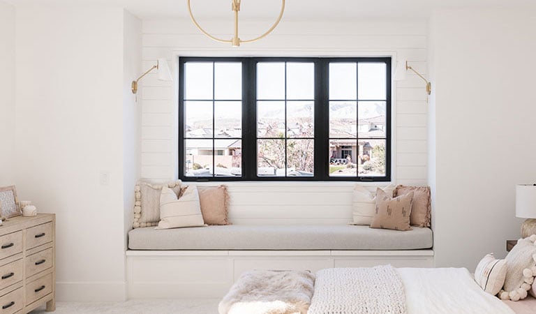 entry with white walls and white bench with a view of andersen 100 series windows with black frames