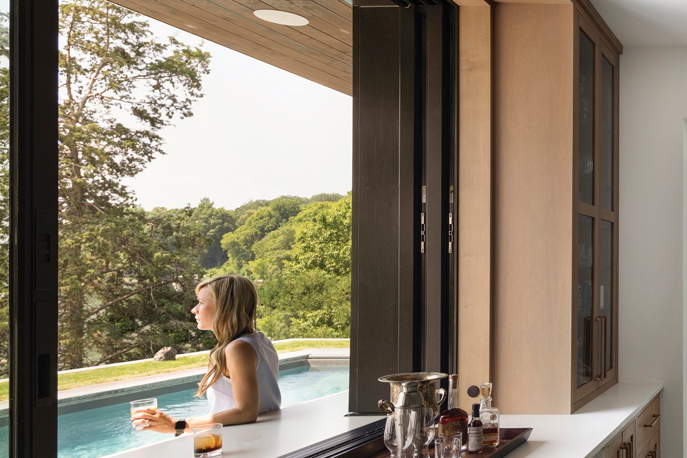 A woman sits outside an open Andersen® MultiGlide™ Pass-Through Window.